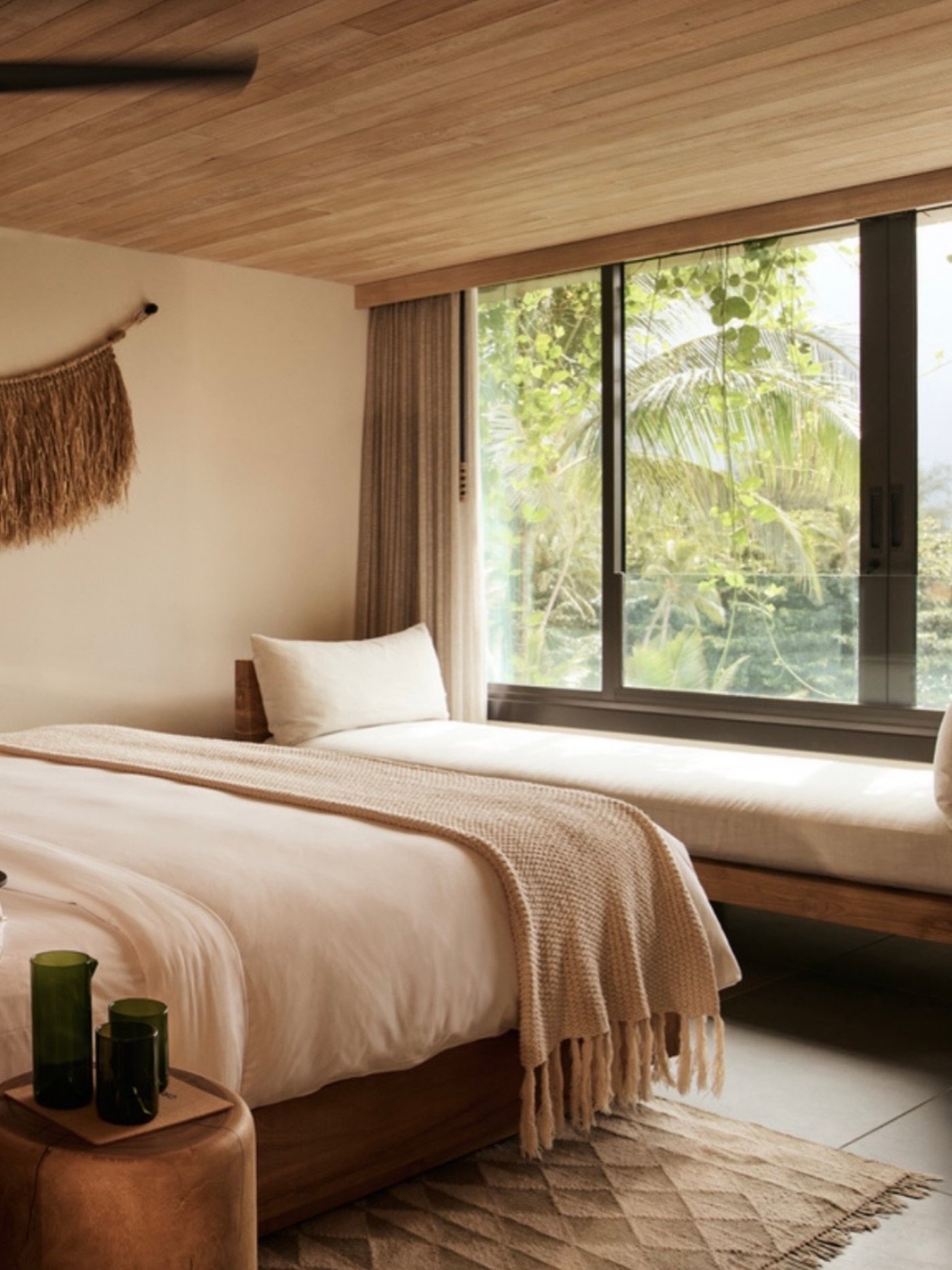 This serene sanctuary celebrates organic textures and a soft, tonal palette, creating a seamless connection to the lush tropical canopy just outside the window. The combination of warm timber ceilings and tactile linens evokes a sense of quiet luxury and effortless calm.