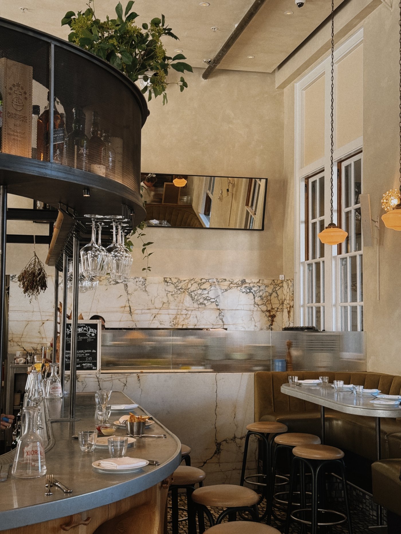A masterclass in layered textures, this sun-bathed bistro pairs dramatic marble veining with soft amber light to create an inviting, golden-hour glow. The space feels both heritage-inspired and distinctly modern, perfect for a long, spirited European-style lunch.
