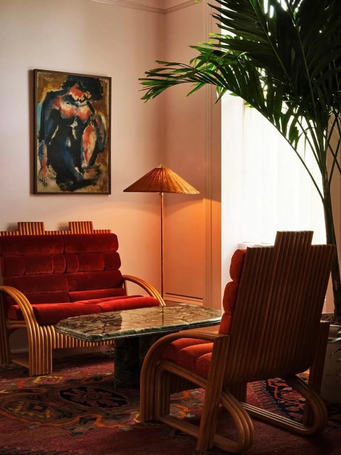 This intimate corner feels like a hushed conversation in a secluded Parisian salon, defined by the rich interplay of tactile cane, plush velvet, and timeworn plaster. The soft glow of a single candle against the textured walls creates an atmosphere of effortless, old-world elegance.