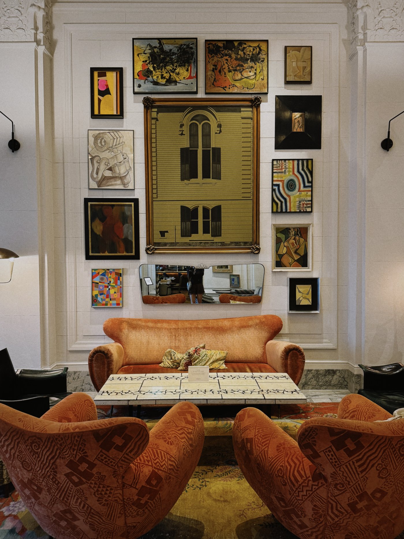 A masterclass in curated maximalism, this lounge space pairs plush terracotta velvets with an eclectic gallery wall that breathes soulful intellect into the room. The juxtaposition of architectural plaster molding and modern abstract art creates an inviting, club-like atmosphere perfect for lingering.