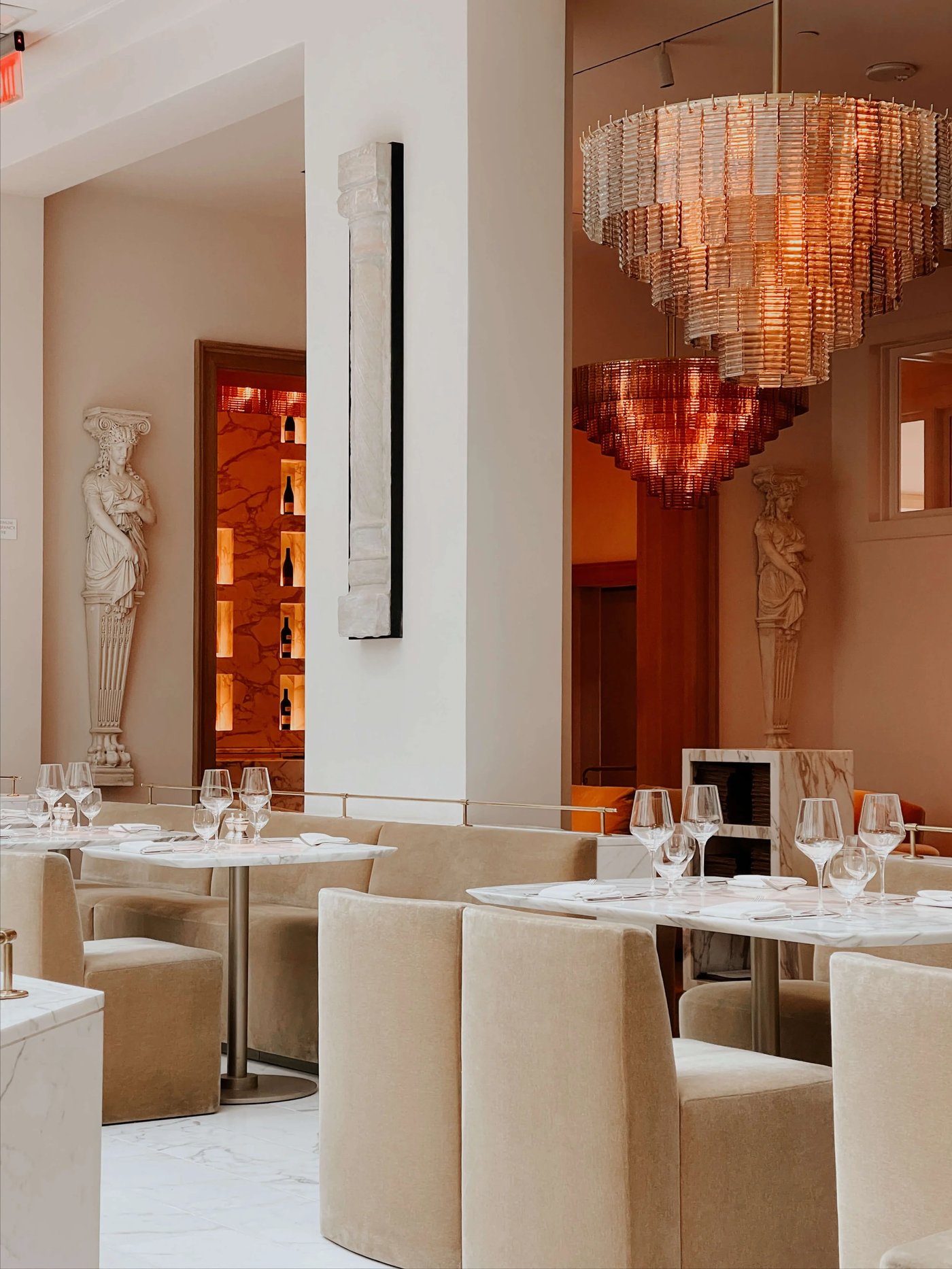 An exquisite blend of classical antiquity and modern luxury, where towering caryatids and tiered crystal chandeliers create a sanctuary of high-vibe refinement. The soft glow of amber light against plush velvet seating makes every moment feel like a scene from a contemporary Roman romance.
